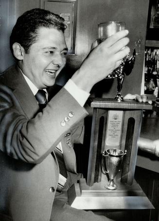Championship toast: Winner of the 1982 Canadian Cocktail Championship, long Drink category, Hector Bedoya of Hemingway's toasts the trophy he received as one of the three winners.