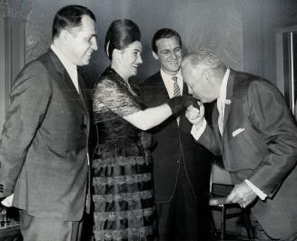 Alan Lamport kisses the hand of Mrs. W. K. Bednarczyk, while her husband, new Polish Consul on her left, watches. On her right, is Stefan Kwiatkowski, outgoing Consul. It's his last reception.