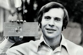One of great Canadian Oil Sands Ltd.'s longterm shareholders, Howard Bertram holds bronze alloy medallion given him and other shareholders as token of thanks by tar sands development firm. The company had a difficult first decade operating its tar sands plant and investors also have taken their lumps. No dividends have been paid on common stock and shareholders watched stock hit alltime high of $17, then fell to current price of $5.