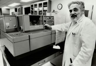 Genius or quack?, Bronx zoologist Lawrence Burton stand beside a spectrophotometer he uses to research his controversial cancer therapies.