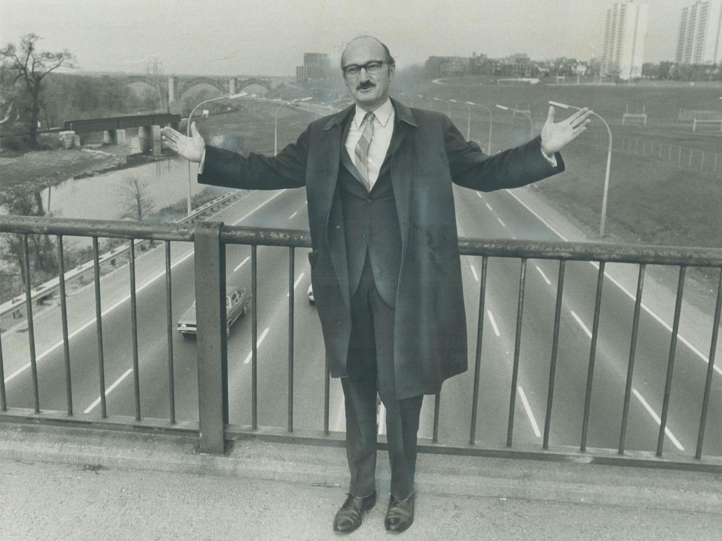 It has to be widened, says Metro traffic commissioner Sam Cass of the Don Valley Parkway as he stands on footbridge crossing it at Riverdale Zoo. Planners estimate it will cost $15 million to widen parkway an extra two lanes, and it's not the right solution adds Cass. In addition, two other street widening programs will cost another $9 million. Cass blames halting of the Spadina Expressway.