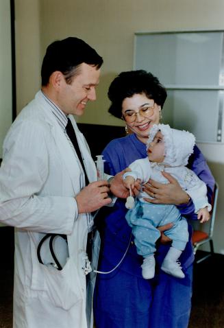 That's no Rattle: Dr. Robert Chisholm shows Parwin Saqib and her baby Neghat a life-saving balloon like the one placed in the woman's hear valve.