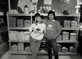 Limited line: Jane Wilson, left, and Simon Clery model of the clothes sold in his boutique at Queen's Quay Terminal. The store carries only sweat shirts, baseball jackets, pants, shorts, tank-tops and short-sleeve cotton shirts bearing the logo of the Upper Canada Brewing Co.