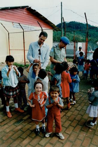 Canadian Forces Capt. Ian Cowan, a military doctor, and helicopter pilot Capt. Jim MacAleese visit with orphaned children living in a Honduran village.