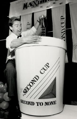 For giant thirsts. Tom Culligan, founder and president of the Second Cup group of coffee houses, pours coffee into a giant cup (in reality a 50-gallon drum) at a meeting of franchisees at the Ramada Renaissance Hotel yesterday. Culligan opened his first outlet 13 years ago.