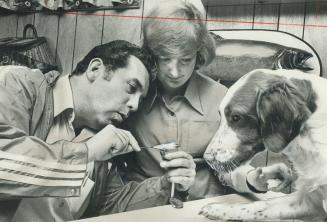 Gordon and Britta Deval take time from casting to tie a few flies, as their Brittany Spaniel, Jamie, looks on.
