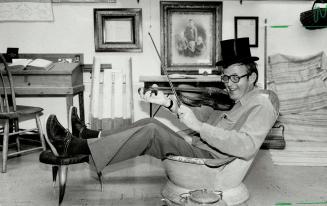 One man in a tub: Ashe Davis, treasurer of King Township Historical Society, relaxes in a 1800s bath tub while stroking a violin dates back to the early 1900s.