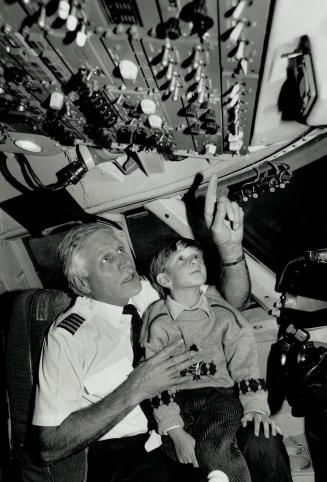 So many switches: Ron Dennis, at the controls of a 747 at Terminal 2, gives his son Andrew, 4, a quick lesson in flight instruments.