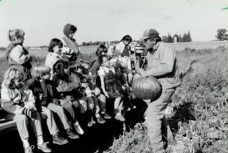 Boo to you: John Downey hoists a prime pumpkin for inspection by grades 1 and 2 pupils from Macville Public School.
