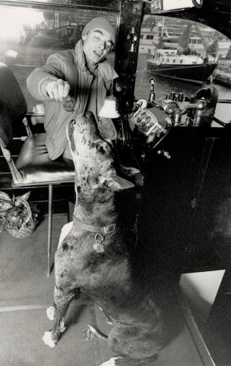 A bite with an old sea dog, Boat restorer Helmut Dressler and his Great Dane Paco share breakfast aboard his craft.