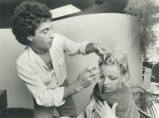 Maurice Fiorio streaks a client's hair with paint applied from a spray can