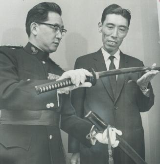 Ancient samurai sword goes home. Major George Suzuki (left), a Japanese-Canadian intelligence officer in World War II, last night completed a personal centennial project by handing centuries-old Samurai sword over to Japanese Vice-Consul Tamotsu Furuta fo