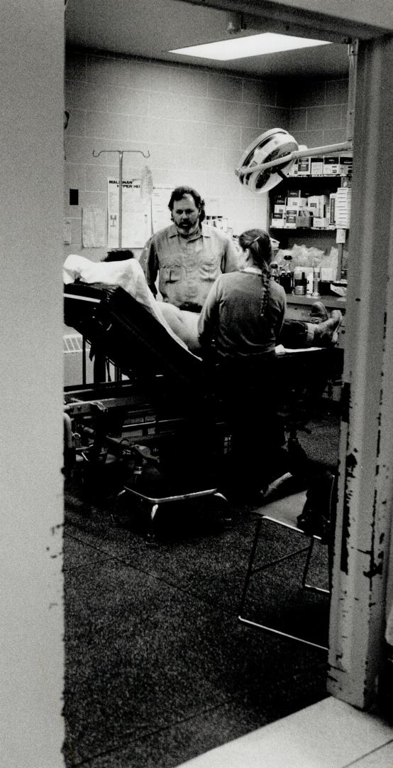 Night shift: Dr. David Fletcher rushes through the deserted corriders of Mount Forest hospital. At right, he examines a late night patient in the emergency room.