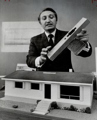 Maurice Fagan, proponent extraordinary of the factory-built house, handles a small but intricate component of the wall studding which goes into pre-engineered houses. Fagan says his systems can save 15 per cent.