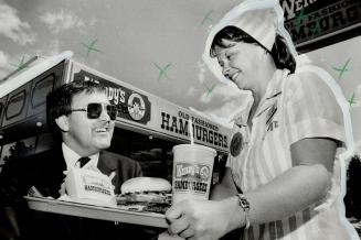 Triple header: Colin Freel, president of Wendy's Restaurants of Canada Inc., is served a triple burger by Debbie Weiss, manager of the company's outlet at the Queensway and Kipling. Freel believes the fast-food industry is going through a shake-down perio