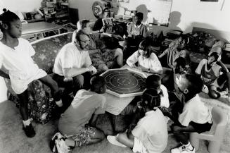 Frank and Wendy Glover enjoy a board game in the family room with some of the 14 children they'vve adopted.
