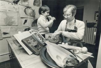 Dr. Anthony Graham, supervised by his celery-chewing son Mark, 3, prepares to stuff a salmon with spinach
