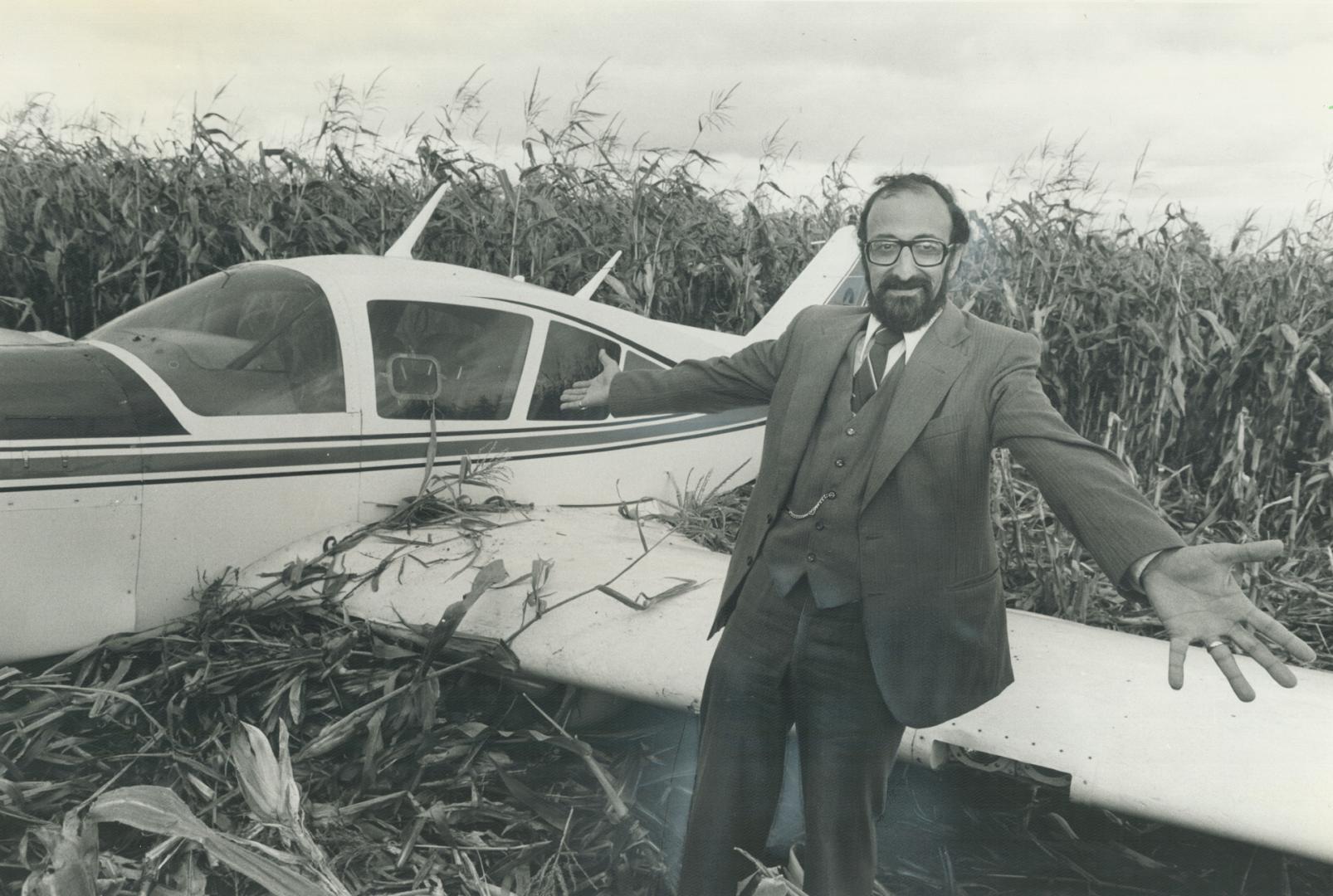 Doctor's dilemma, Dr. Andreas Haralampides, 40, of Uxbridge throws up his hands at his crashed plane after making a forced landing in a cornfield near Markham. His Passenger, Gordon Land, 37, of Oshawa had only six months ago made ago made a similar forced landing in a Mississauga field with Haralampides piloting the same plane.