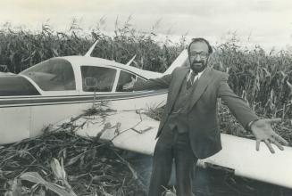 Doctor's dilemma, Dr. Andreas Haralampides, 40, of Uxbridge throws up his hands at his crashed plane after making a forced landing in a cornfield near Markham. His Passenger, Gordon Land, 37, of Oshawa had only six months ago made ago made a similar forced landing in a Mississauga field with Haralampides piloting the same plane.