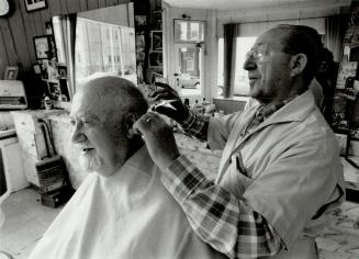Getting clipped, Martin Lewis, 77, gets his hair cut by Pasquale Guerriero, owner of Pasquaie Barber Shop at the corner of McCaul and D'Arcy sts.