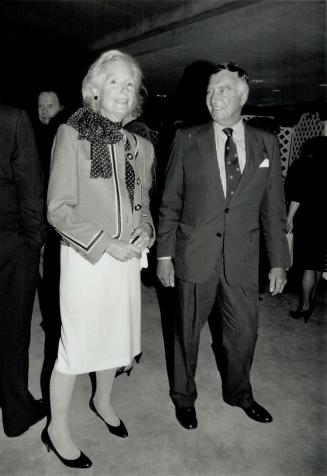 Anita McClelland in a Chanel-style hot pink jacket, navy-and-white polka dot blouse, chats with architect Douglas C. Haldenby.