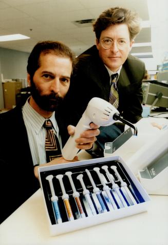 Glenn Harvey, left, and John Kennedy with their battery-powered unit that uses burst of light to cure dental fillings and other materials.