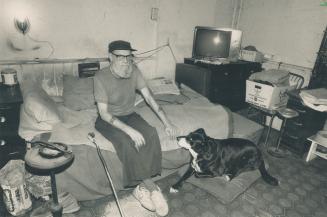 Under siege: Archie Kerr, 68, seen with dog Tippie, sits in his rented room while the house is being gutted around him
