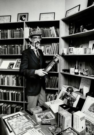 A bearded man in a deerstalker hat with a pipe holds a violin in front of books and collectable…