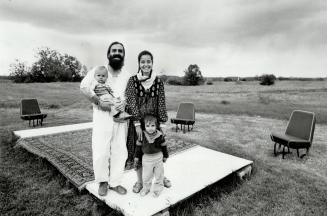 Settin for thinking: Former psychology professor Chris Holmes, his wife, Anita, and children Matthew, 2 1/2 andTimothy, 1, stand onthe outdoor stage where Holmes runs open-air seminars on mysticism and spiritual science amid the peaceful rolling hill of Maple