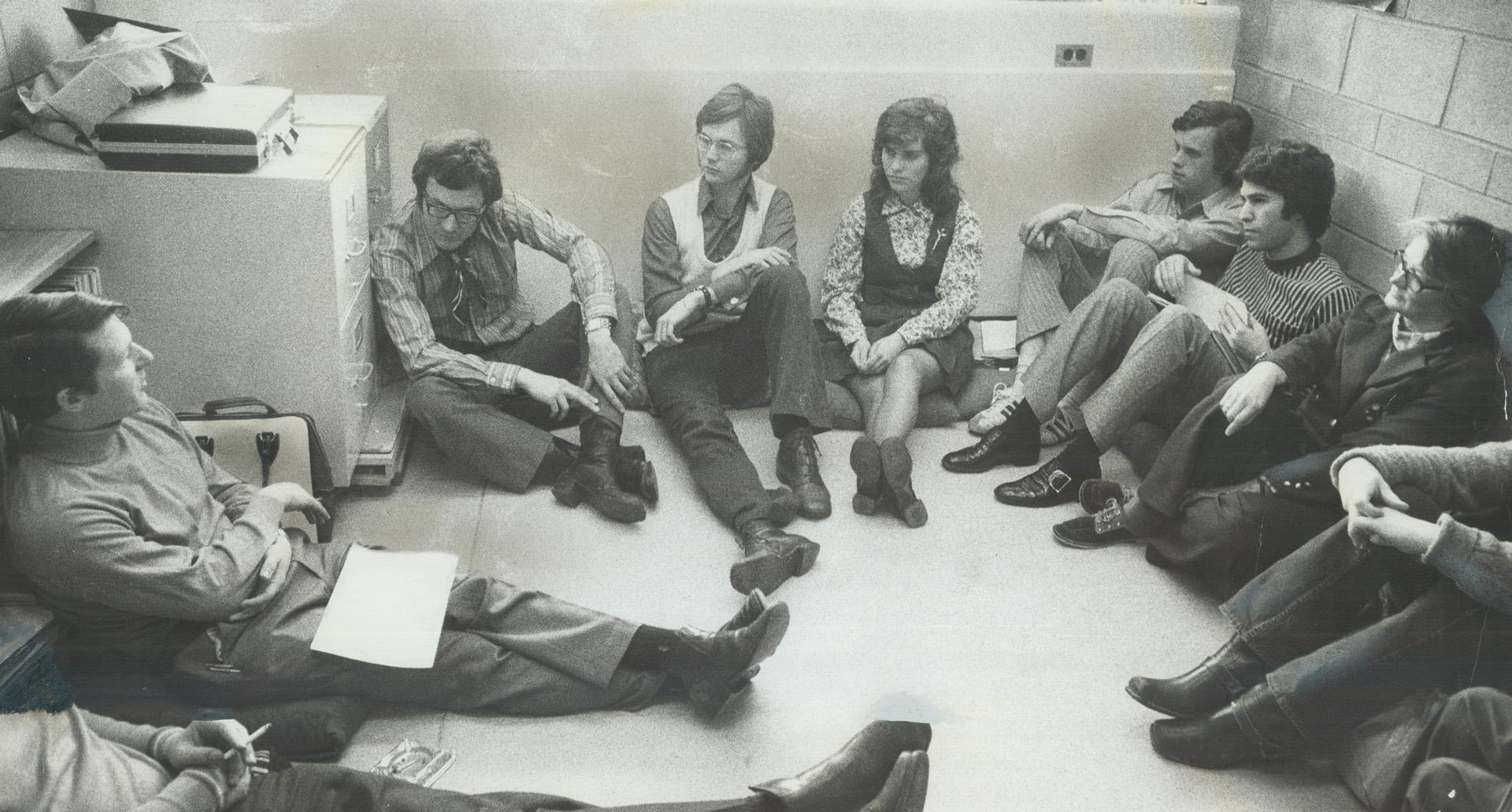 Taking a study session, Professor John Lee, in striped shirt, Jeans against filing cabinet as he makes a point to students at the University of Toronto's Scarborough College