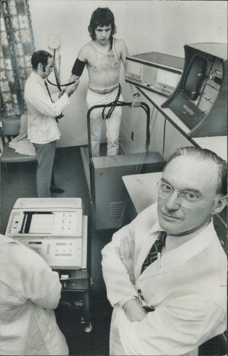 Dr. J. A Little (front) is project director of a heart research program in St. Michael's hospital. Ari Haukioja runs on treadmill of ECG machine while Dr. Joseph Bruni (left) takes his blood pressure.