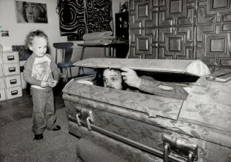 Guest room: John Leslie checks out his new guest room -- a coffin -- for size, as son Mitchell, 2, looks on