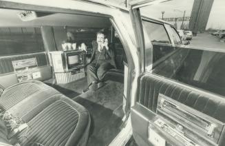 Lap of luxury: Those long, long limousines that seem to be on every street corner these days contain all kinds of gadgets, including telephones - handy for Harry Malawi, owner of First Choice Limousine Service