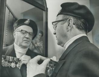 Charles Martin pins on the medals he won during World War II