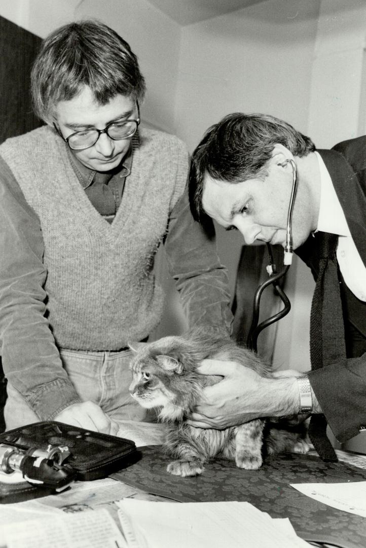 Hold still! Veterinarian Dr. Terry McGarragle, with Sophie Arthaud's help, examines one of six cats that he comes to see once a year in Arthaud's Cabbagetown home.