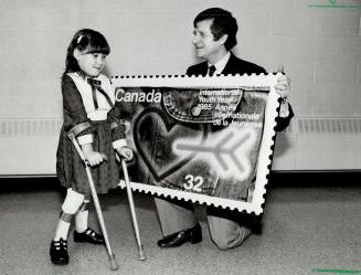 Stamp unveiled: Robyn Waskies, 7, a Grade 2 pupil, helps Canada Post chairman Rene Marin unveil a poster-sized version of a new stamp in honor of International Youth Year