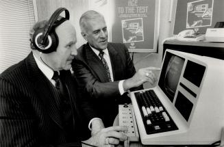 Mutal life insurance agent Donald James, left, tries his hand at high-tech biological age testing on computer as president and chief executive officer Jack Masterman Watches