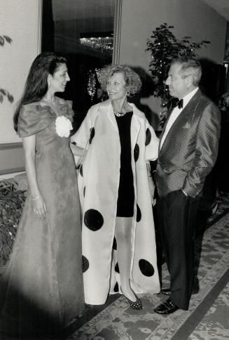 Ball Chairman Julia Paisley, left, wearing a red gown by Scaasi, greets Pauline Menkes, in a gazar coat over a silk jersey dress by Isaac Mizrahi