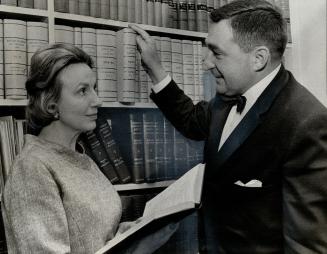 Mr. and Mrs. C. M. Neiman, two-thirds of the law firm of Neiman, Bissett and Seguin, consult law books in Mr. Neiman's office. Mrs,. Neiman, who's been a candidate in an Ontario election, spends three days a week in the law office. Their partnership began with marriage while they were students at Osgoode Hall.