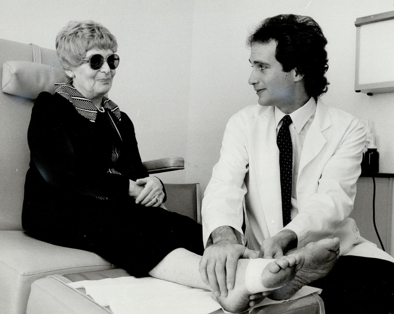 Best foot forward: Dr. Sheldon Nada, embulator foot surgeon, discusses his less painful surgical techniques with senior patient Mary Carter in his Eglinton Ave. E. Office. In most cases just Aspirin is needed for discomfort and casts, crutches and pins are not used.