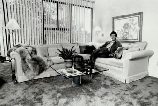 Den delight: Interior designer Bryon Patton of L'Image Design (above), who worked with the Forrests on the condo's interior, relaxes in the den, featuring traditional sofa updated with nubby natural linen, and with fur throw and cushions