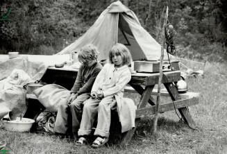 It's cold and wet: Joe Pearce, 8, and his sister Diane, 9, huddle on a picnic bench in front of the tent they all call home in Woodland Park off Steeles Ave
