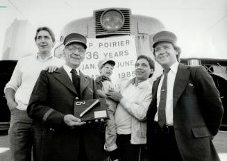 A family affair: Retiring conductor Phil Poirer, holding commemorative gold spike, stands in front of train with sons Michael, left, John (holding his son Brad) and Paul