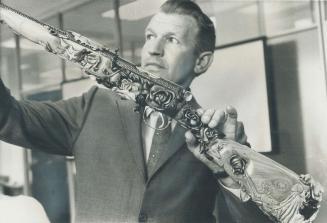 Hans Rasmussen holds a delicately carved Lee Enfield rifle which is an example of the artistic talent of his wife Heidy