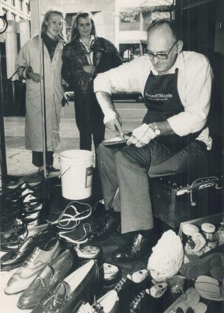 Shoes fit for a president, Passersby watch Raymond Robinson at work in a window of Harry Rosen on Bloor St.