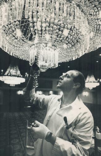 Cleaning up: Gary Rochon wears a white laboratory coat and white gloves to clean the chandelier in the Royal York Hotel's concert hall
