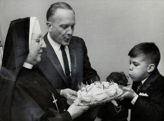 Dennis Ridout, 10, celebrates his birthday that almost didn't come to pass, Sister Marie de Liesse and the doctor who delivered Dennis, Dr. Bob Robinson, help blow out candles