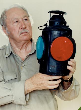 Lamp collector: Colonel Andrew Ritchie of Etobicoke who has made a study of lanterns, especially those used by the railways, shows one of his old signal lamps, a CNR switch marker