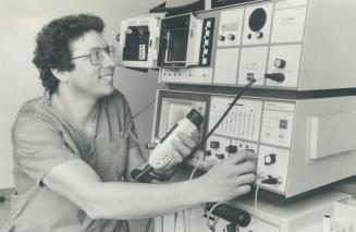 $170,000 detective: Dr. Kal Schneider, of Etobicoke General Hospital's radiology department, is all smiles as he demonstrates hospital's new ultrasound machine, in which sound waves are used to obtain pictures of the body's internal organs, including the heart. Schneider is holding a transducer, which sends out sound wave.