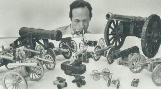 Taking aim along the barrel of one cannon, Clarence I, Scott shows off the collection of 23 minature antique cannons he has collected over the past seven years